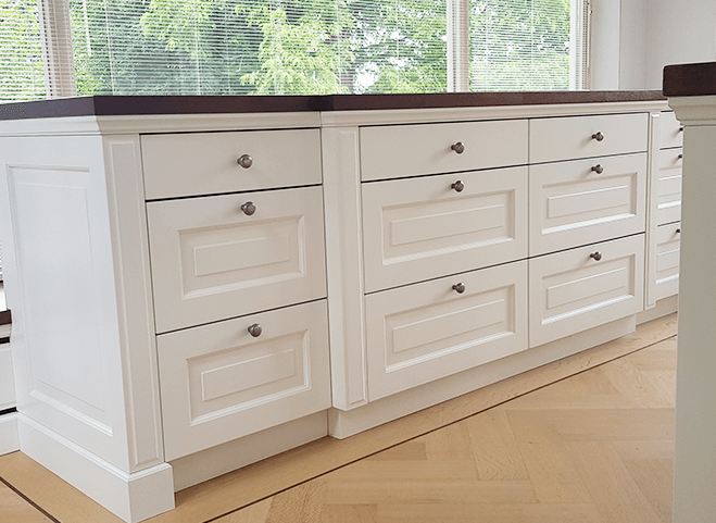 Luxe witte design keuken met glazen schuifdeuren, houten werkblad en moderne inbouwapparatuur.