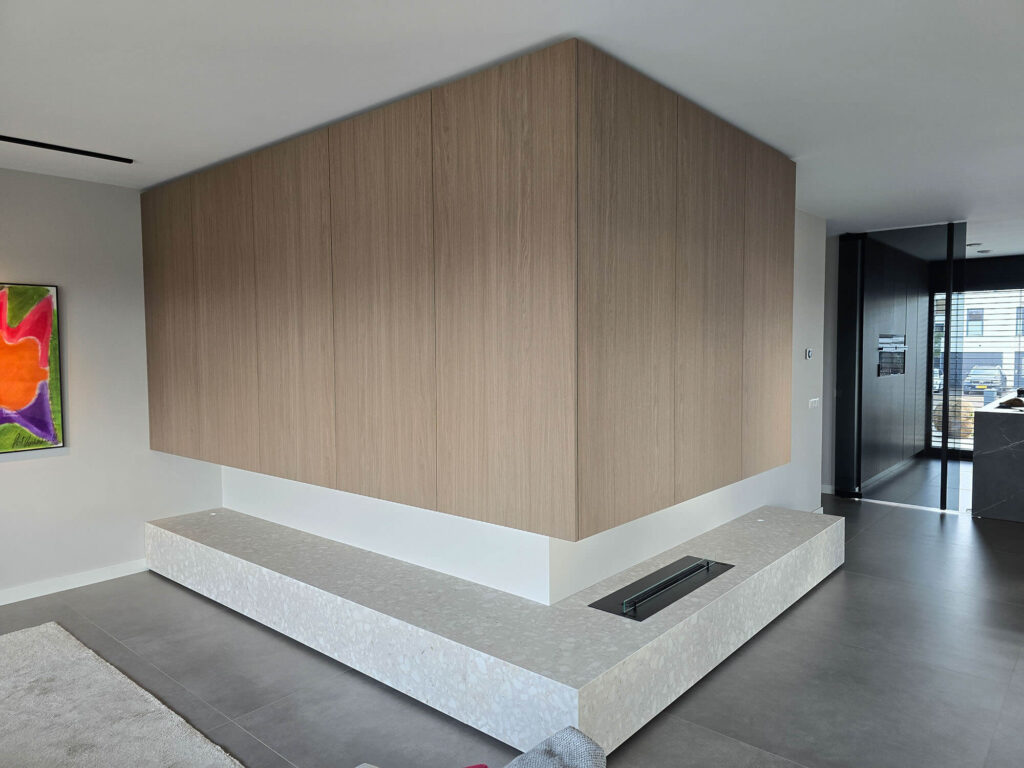 Moderne woonkamerinrichting in Roermond met op maat gemaakt TV meubel, wandkast, verlichting en gashaard.