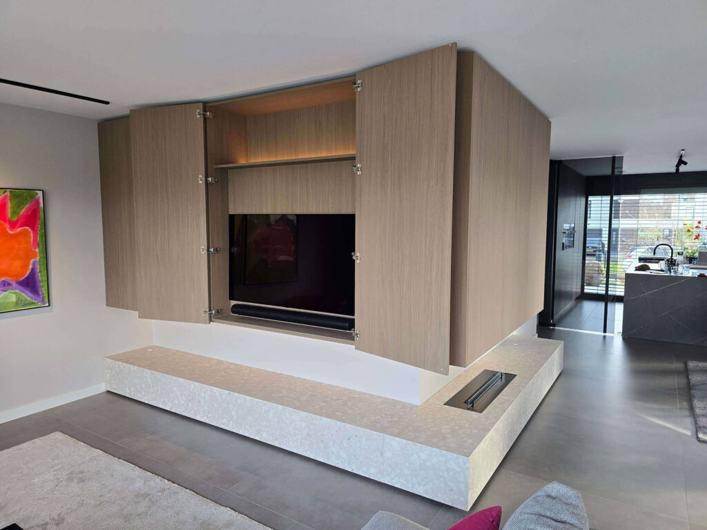 Moderne woonkamerinrichting in Roermond met op maat gemaakt TV meubel, wandkast, verlichting en gashaard.
